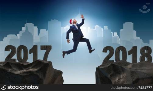 The businessman in santa hat jumping from 2017 to 2018. Businessman in santa hat jumping from 2017 to 2018
