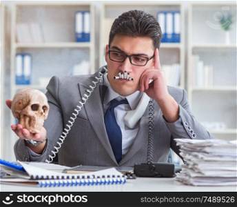 The businessman in the office smoking holding human skull. Businessman in the office smoking holding human skull