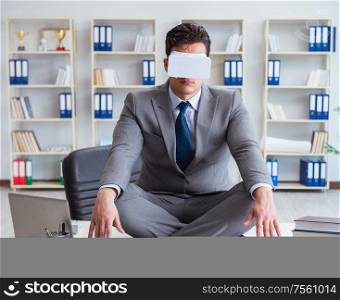 The businessman in virtual reality vr glasses meditating at desk top. Businessman in virtual reality VR glasses meditating at desk top
