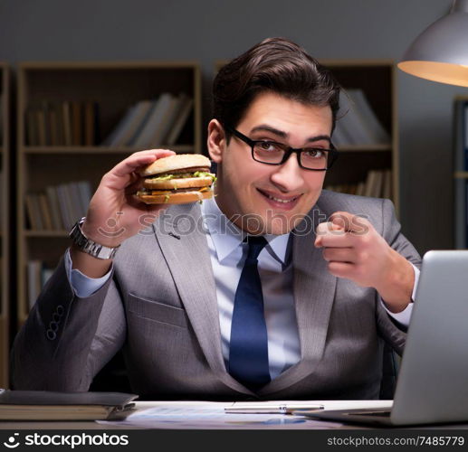 The businessman late at night eating a burger. Businessman late at night eating a burger