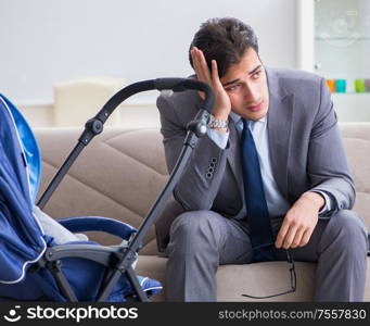 The businessman looking after newborn baby at home and teleworking. Businessman looking after newborn baby at home and teleworking