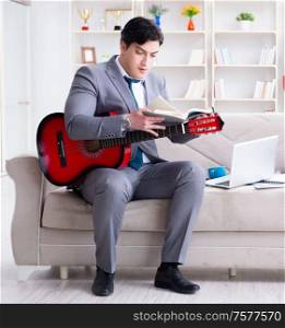 The businessman playing guitar at home. Businessman playing guitar at home