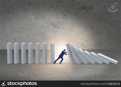 The businessman preventing domino effect in business concept. Businessman preventing domino effect in business concept