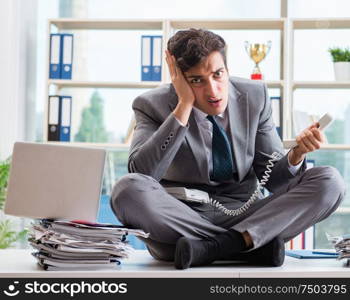 The businessman sitting on top of desk in office. Businessman sitting on top of desk in office