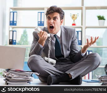 The businessman sitting on top of desk in office. Businessman sitting on top of desk in office