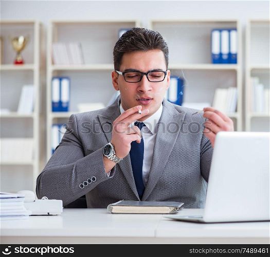 The businessman smoking in office at work. Businessman smoking in office at work