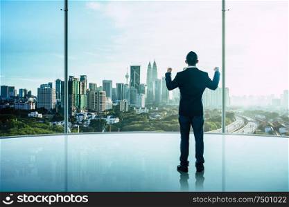 The businessman was very excited in the office with modern city skyline .