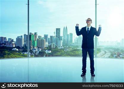 The businessman was very excited in the office with modern city skyline .