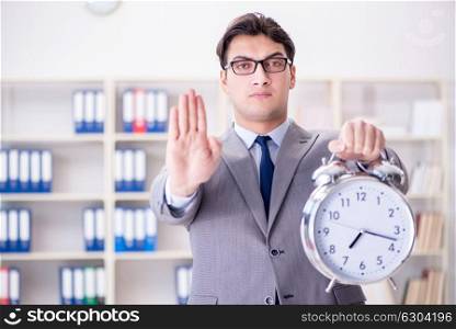 The businessman with alarm clock in the office. Businessman with alarm clock in the office