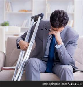 The businessman with crutches and broken leg at home working. Businessman with crutches and broken leg at home working