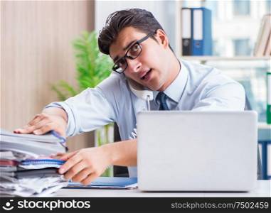 The businessman with excessive work paperwork working in office. Businessman with excessive work paperwork working in office