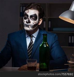 The businessman with scary face mask working late in office. Businessman with scary face mask working late in office