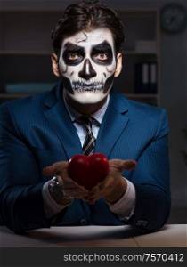 The businessman with scary face mask working late in office. Businessman with scary face mask working late in office