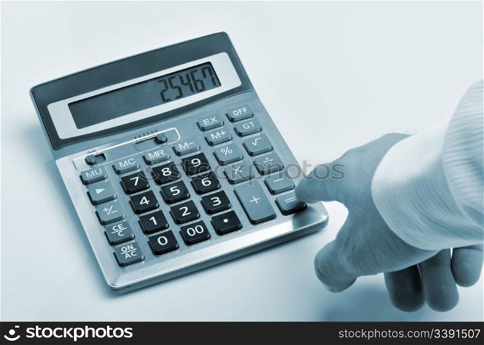 The calculator and a hand of the man. Pressing of a key of the calculator