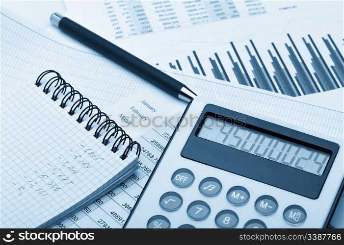 The calculator and the financial report blue toned. A workplace of the businessman