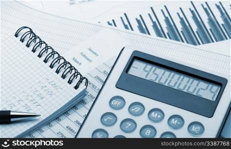 The calculator and the financial report blue toned. A workplace of the businessman