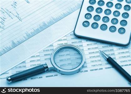 The calculator,loupe and the financial report blue tone. A workplace of the businessman