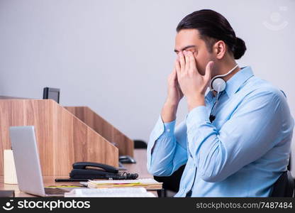 The call center operator working at his desk. Call center operator working at his desk