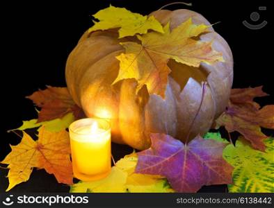 The candle burns before pumpkin with a maple leaf