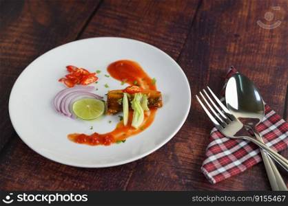 The canned sardine with tomato sauce and cooking ingredient was beautiful arrangement in white plate, stainless spoon and fork on napkin placed nearly on wooden table, copy space