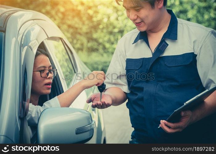 The car mechanic is describing the details of the car inspection. For women who own For understanding before repairing. The customer sends the car key to the mechanic.