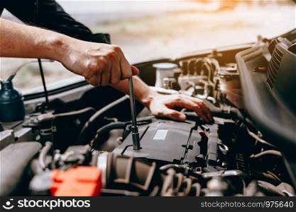 The car mechanic uses a wrench to open the car's engine box.