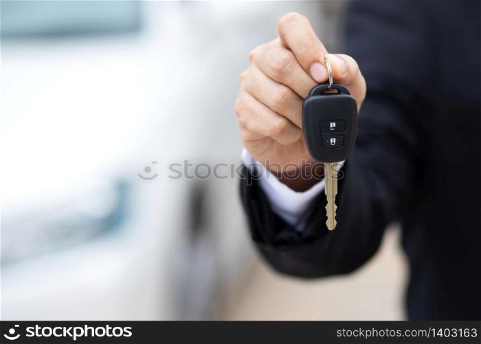 The car salesman is delivering the new car keys to the customers at the showroom.