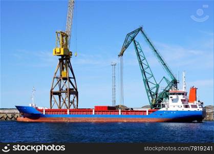 The cargoship and the crane on a background of the blue sky