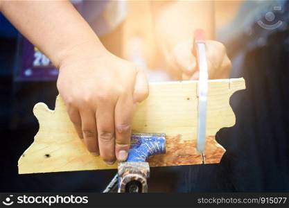 The carpenter is using a saw to cut wood. A carpenter, a man, made a saw of wood, paper The background is glazed with yellow gold bokeh.