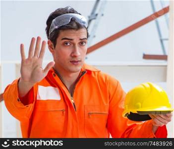 The carpenter wearing yellow hardhat in contractor workshop. Carpenter wearing yellow hardhat in contractor workshop