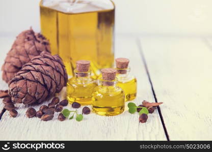 The cedar oil in a glass bottle. The cedar oil in a glass bottle on a white wooden background. Source of essential fatty acids for healthy nutrition