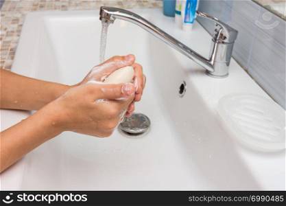 The child carefully soaps his hands with soap