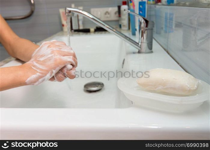 The child carefully washes his hands with soap, in the foreground a bar of soap