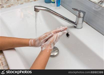 The child carefully washes his hands with soap suds