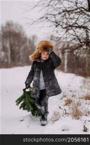 The child got a Christmas tree in the forest to decorate the house for the holiday.. A child in the snow carries a Christmas tree home from the forest 3123.