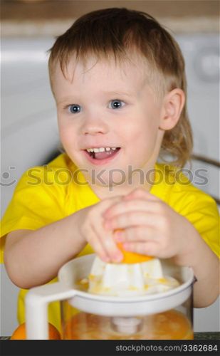 The child in a yellow vest to wring out juice from an orange