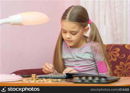 The child looks at a coin album for collectibles