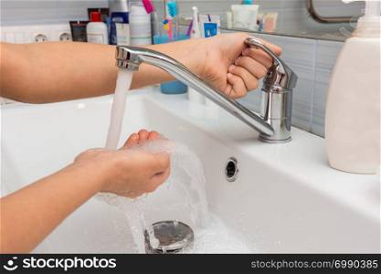 The child opens the faucet in the bathroom, and adjusts the warmth of the water