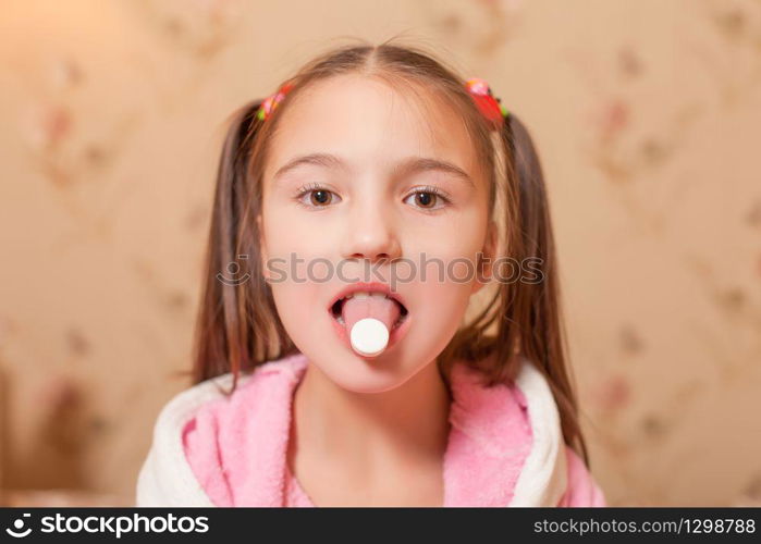 The child with a tablet on tongue. Child illness concept.