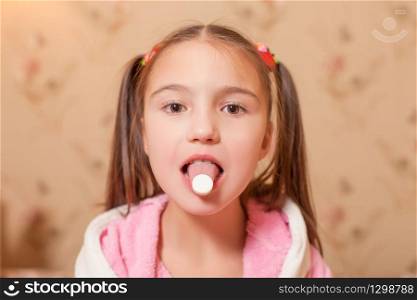 The child with a tablet on tongue. Child illness concept.