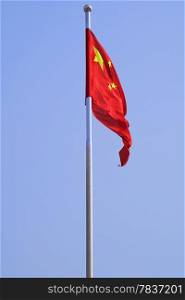 The Chinese Flag Flapping Against A Solid Blue Sky