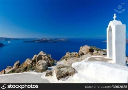 The church arch with cross on top of a mountain over island Santorini and village Oia. Greece.. Oia. Aerial view of the village from above.