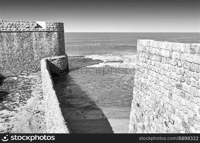 The city beach located adjacent to the sea walls of Akko in Israel. View on a fortification of an old city Akko, a small Israeli port town with ruins dating 4000 years. Black and white picture