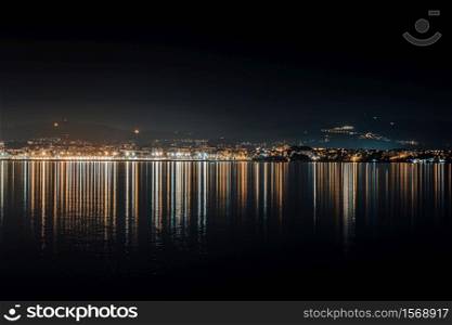 The city skyline lights reflecting in the sea during the night