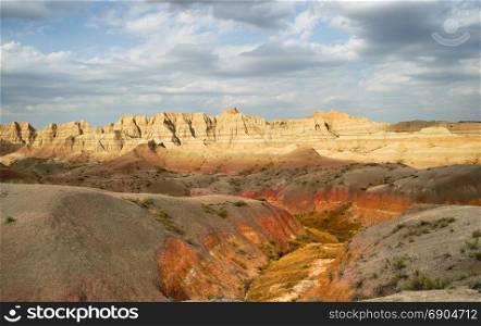 The clouds allow the sun to light rock formations in the South Dakota Badlands