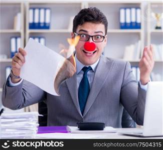 The clown businessman burning paper papers in the office. Clown businessman burning paper papers in the office