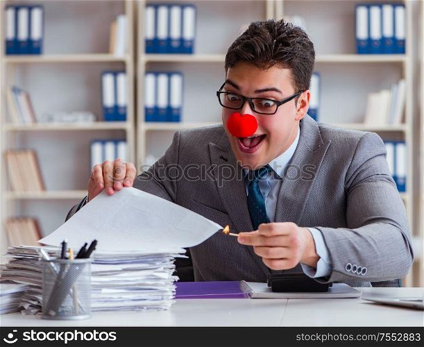 The clown businessman burning paper papers in the office. Clown businessman burning paper papers in the office