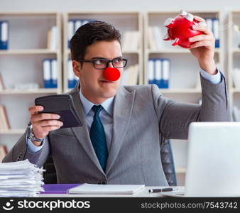 The clown businessman with piggy bank doing accounting. Clown businessman with piggy bank doing accounting