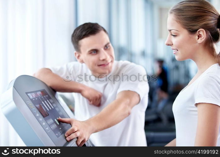 The coach helps a girl in a fitness club