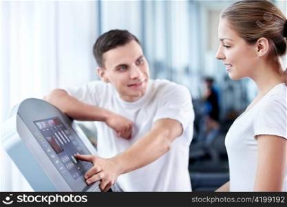 The coach helps a girl in a fitness club